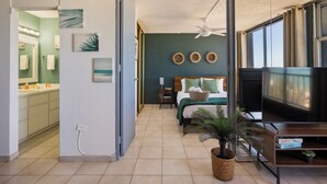 Un dormitorio con cama, televisión, mesita de noche y ventana.