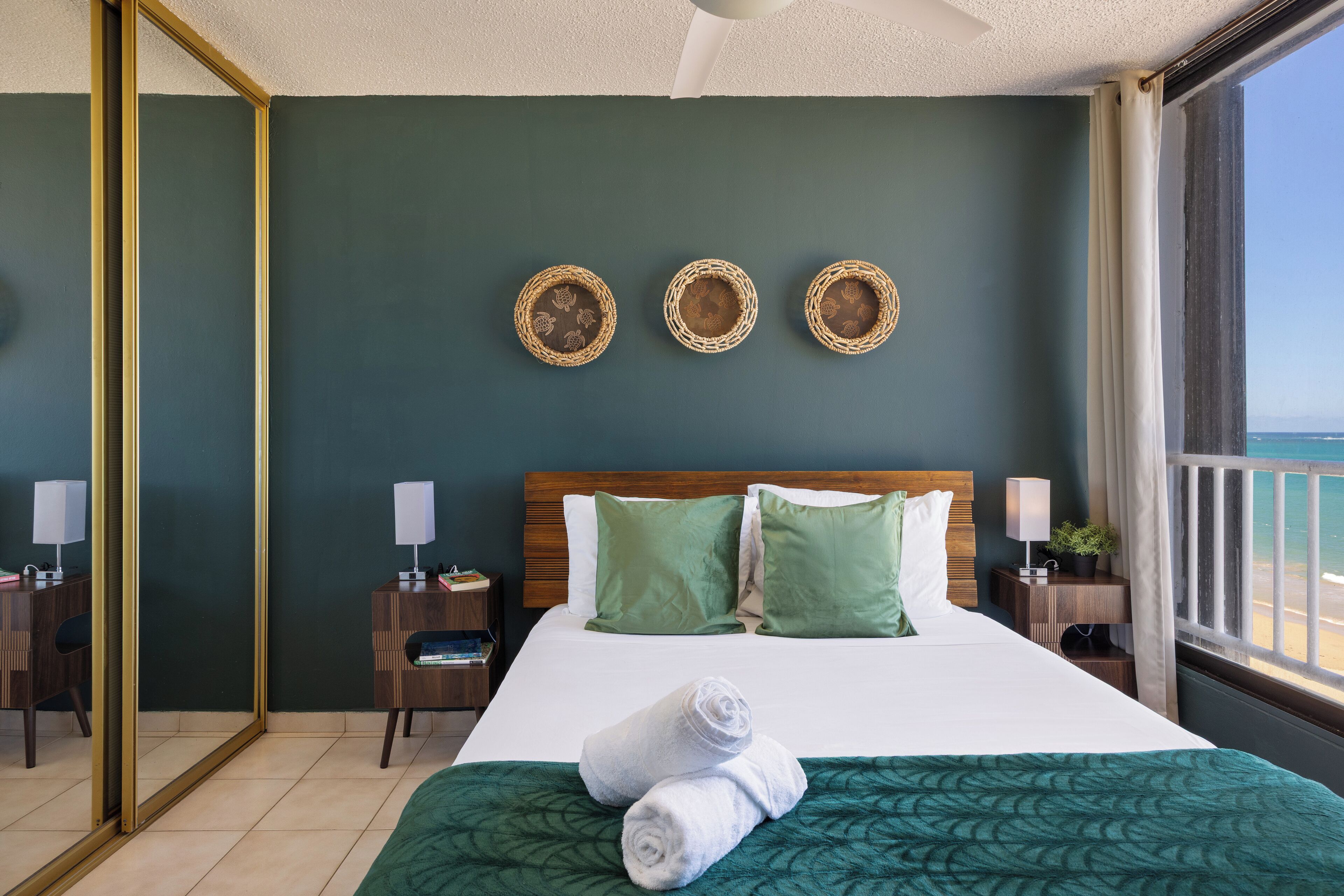 A hotel room with a large bed, green walls, and a view of the sea.