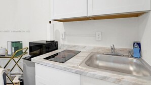A kitchen with white cabinets, a stainless steel sink, a black microwave, and a glass coffee maker. - HOT TUB + WASHER AND DRYER in Unit / MIAMI (Miami)