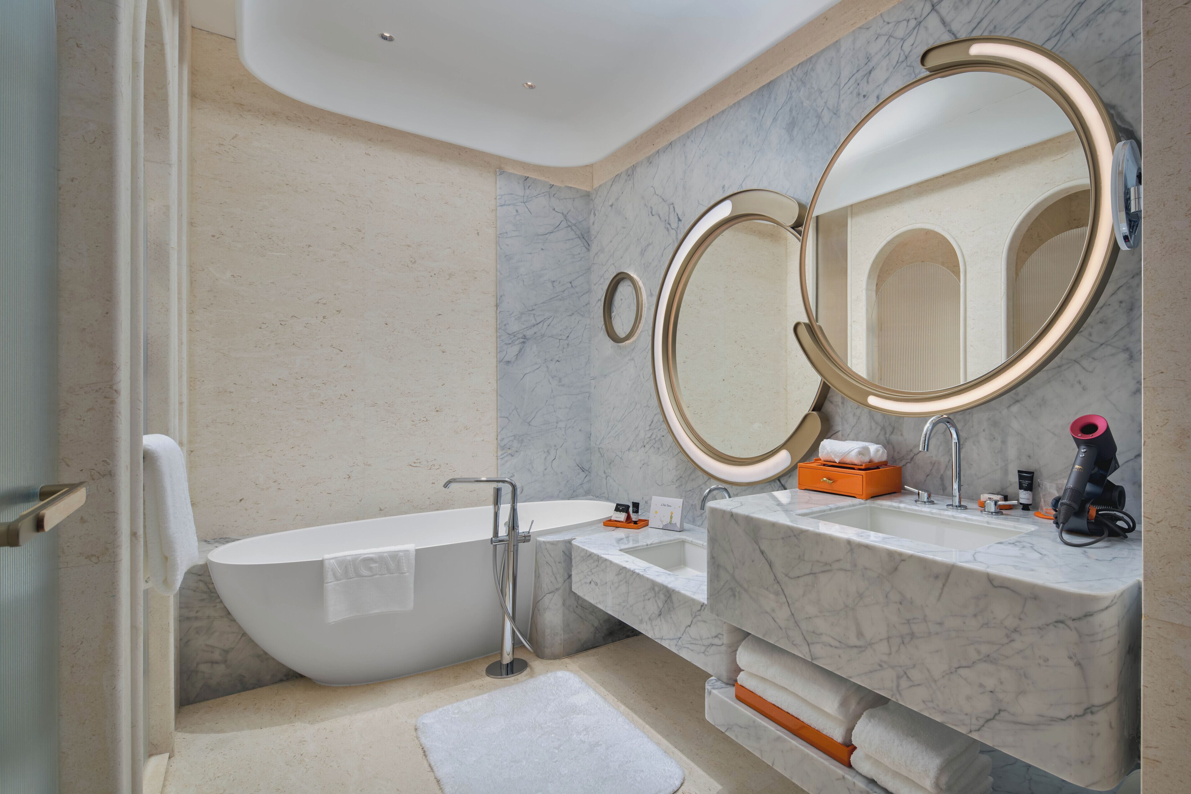 A modern bathroom with a freestanding bathtub, a sink with a marble countertop, and two wall-mounted mirrors.