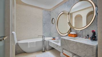 A modern bathroom with a freestanding bathtub, a sink with a marble countertop, and two wall-mounted mirrors.