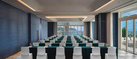 A conference room with a long table, white chairs, and a blue carpet.