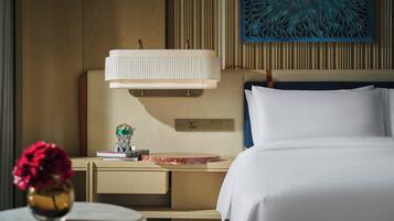 A hotel room with a bed, bedside table, lamp, and artwork on the wall.