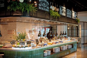 A buffet counter with various food items and drinks, surrounded by hanging plants and decorative elements. - MGM Shenzhen (Shenzhen)