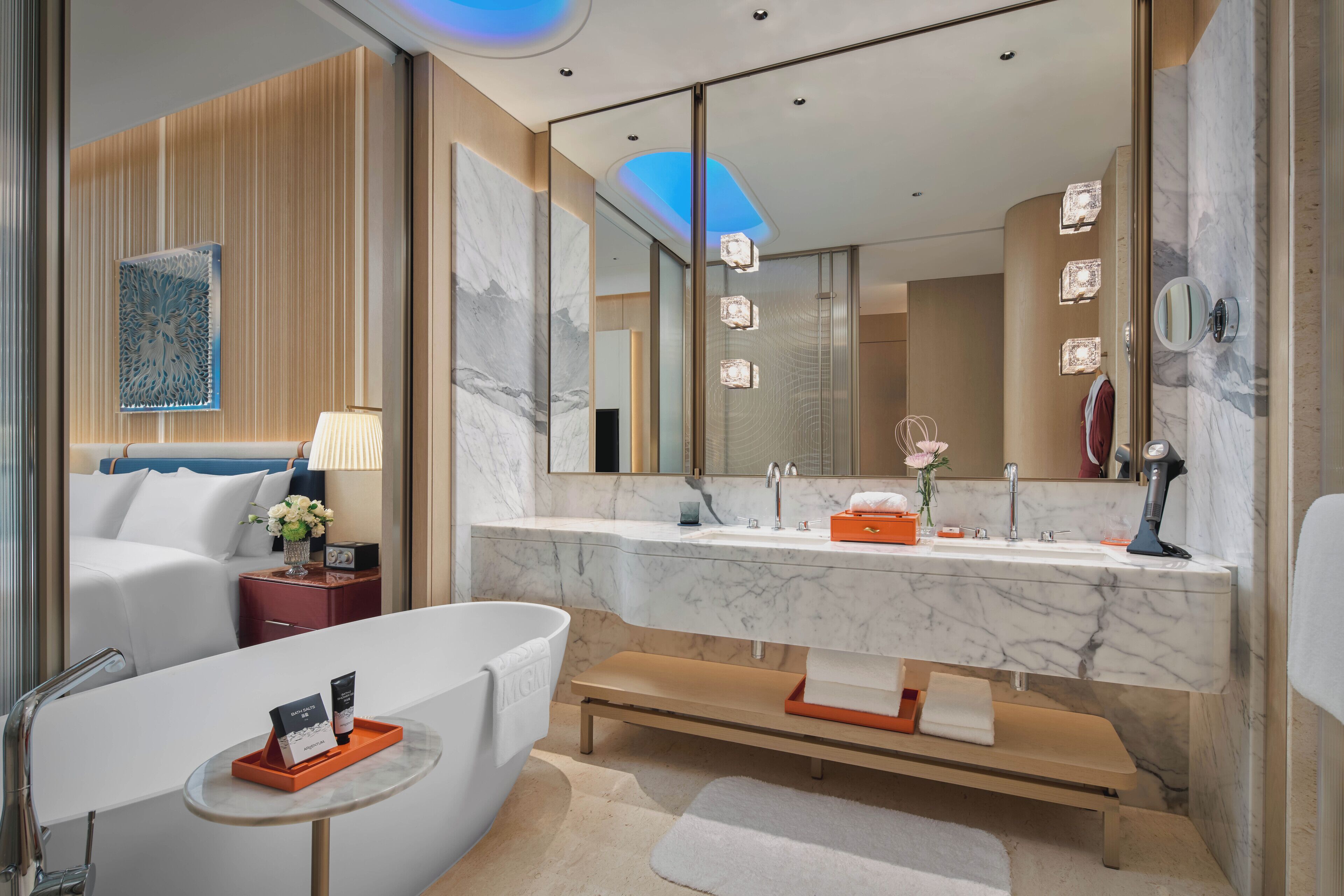 A modern bathroom with a marble vanity, a large mirror, and a bathtub.