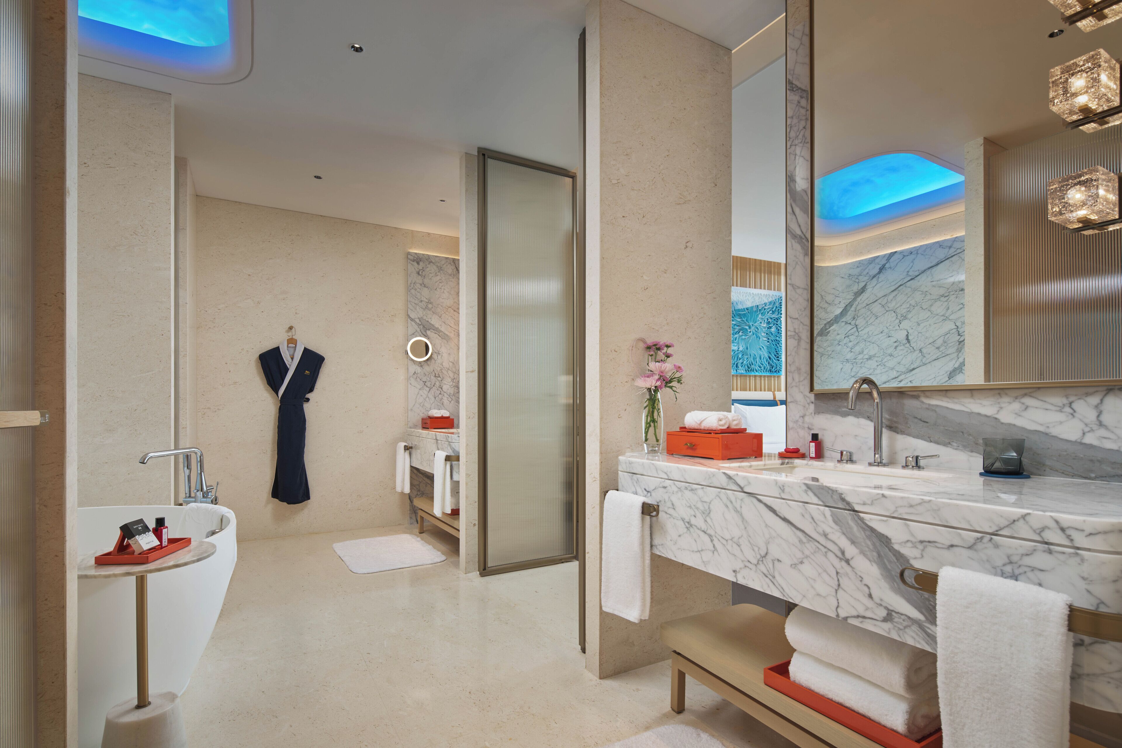A modern bathroom with a marble vanity, a separate sink, and a walk-in shower.