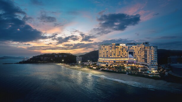 A large, multi-story hotel with a prominent 'MGM' sign, situated by a beach with a view of the sea and mountains in the background. - MGM Shenzhen (Shenzhen)