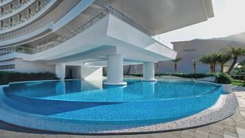 A modern hotel with a central pool, multiple floors, and a distinctive architectural design.