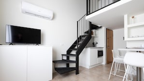 A modern kitchen with a black staircase, white cabinetry, a flat-screen TV, and a microwave. - Italianway - Metastasio 3 int 58 (Milan)