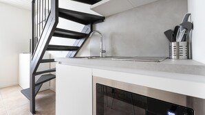 A modern kitchen with a built-in dishwasher, a stainless steel sink, and a black staircase. - Italianway - Metastasio 3 int 58 (Milan)