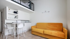 A compact living space with a kitchenette, a sofa, and two bar stools. - Italianway - Metastasio 3 int 58 (Milan)