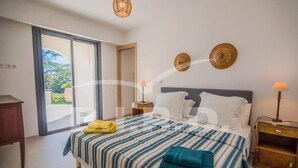 A bedroom with a bed, a nightstand, a lamp, and a view of the outdoors. - Sainte Maxime Beautiful villa with sea view at 300m from the beach (STE MAXIME)