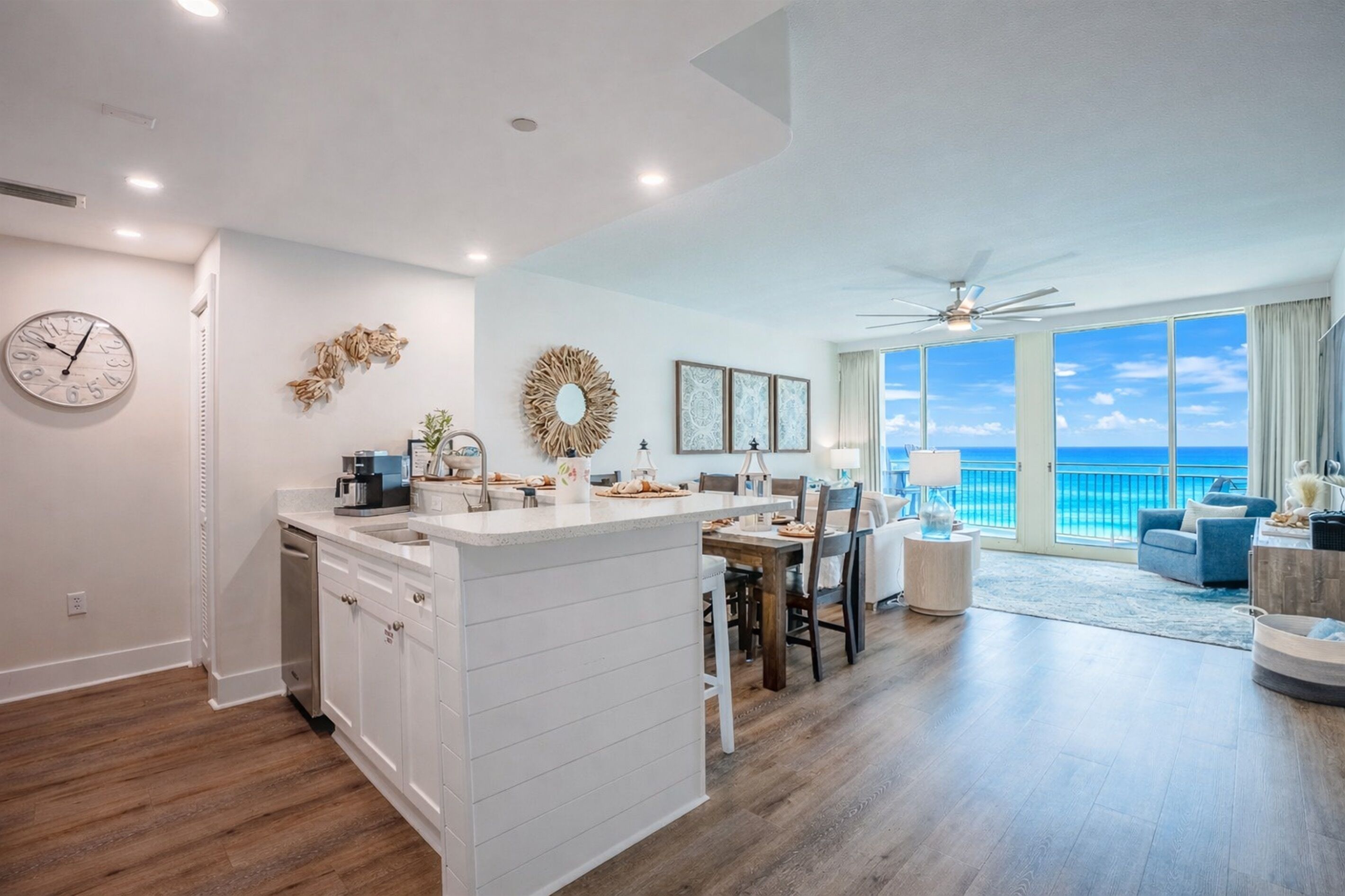 Una cocina moderna con una isla central, un comedor con vistas y una sala de estar con un amplio ventanal con vista al océano.