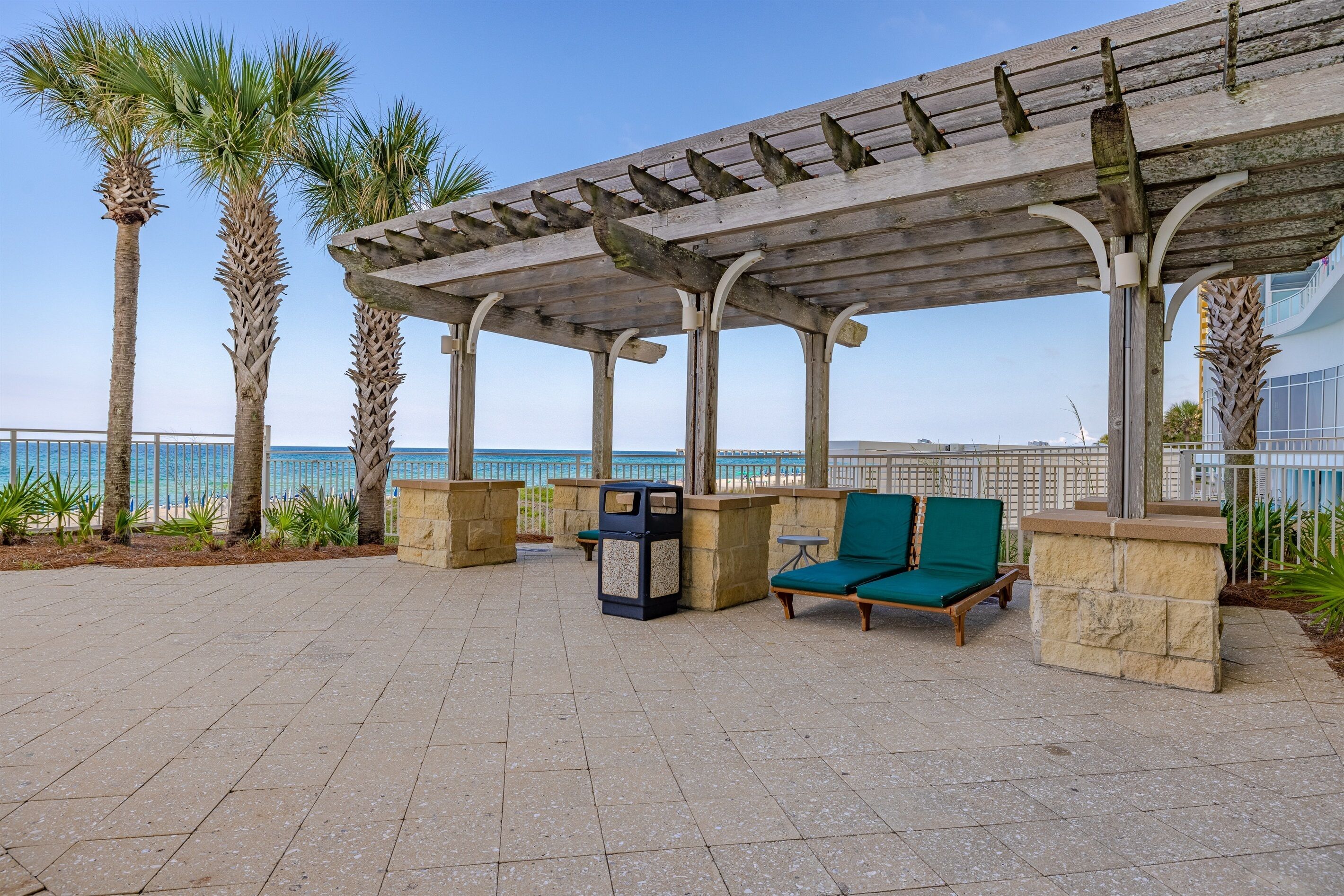 Ein überdachter Außenbereich mit Steinpfeilern, einer Holzpergola und Blick auf das Meer.