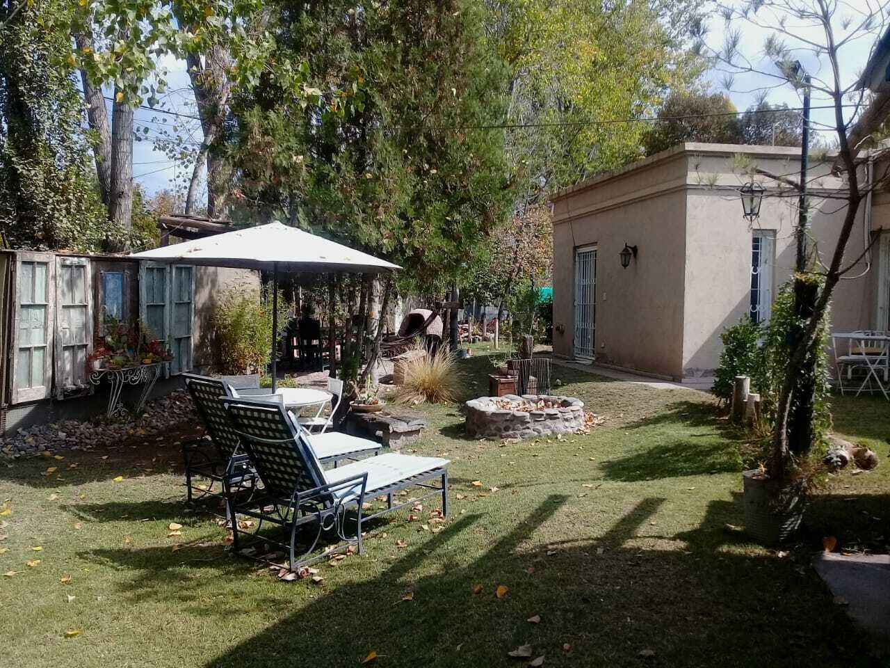 A backyard with a covered patio, outdoor seating, and a small fire pit.