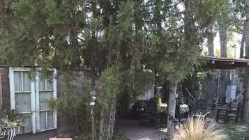 Un patio trasero con una mesa y sillas de madera, una maceta de piedra y un pequeño estanque.