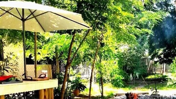 An outdoor dining area with a stone fire pit and a table set for a meal. - Dark Green House - Chacras de Coria (Chacras de Coria)