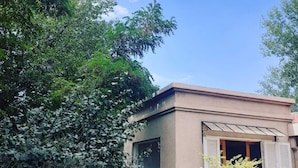 A building with a beige facade, large windows, and shutters. - Dark Green House - Chacras de Coria (Chacras de Coria)