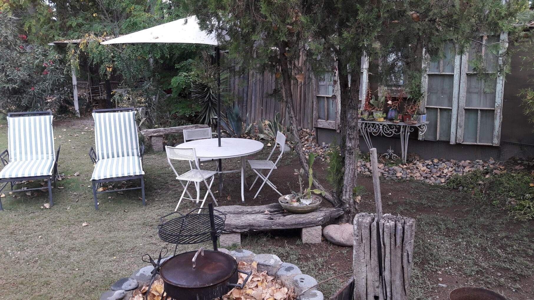 An outdoor patio with a round table and chairs, a fire pit, and a covered seating area.