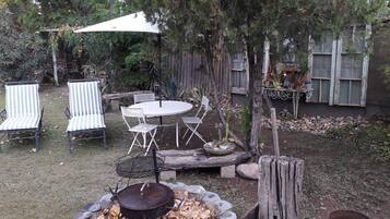 An outdoor patio with a round table and chairs, a fire pit, and a covered seating area.