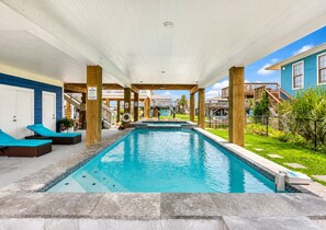 Une piscine avec des chaises longues et un espace abrité doté de poutres en bois.
