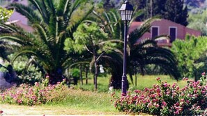 A street lamp in a garden with palm trees and flowers. - Apartment Type A in Costa Saracena - Castelluccio (Augusta)