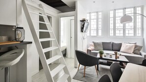 A modern living space with a white staircase, a grey sofa set, and a dining area. - The Little Rousseau - Cosy & Calm byMon Petit Faré (Paris)