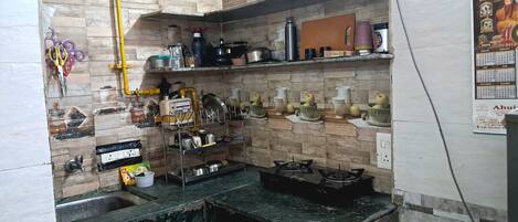 Een koelkast, een kookplaat, kookgerei, borden en bestek