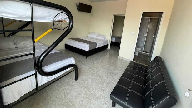 Une chambre de type dortoir, avec des lits superposés, un banc et un petit coin salon.