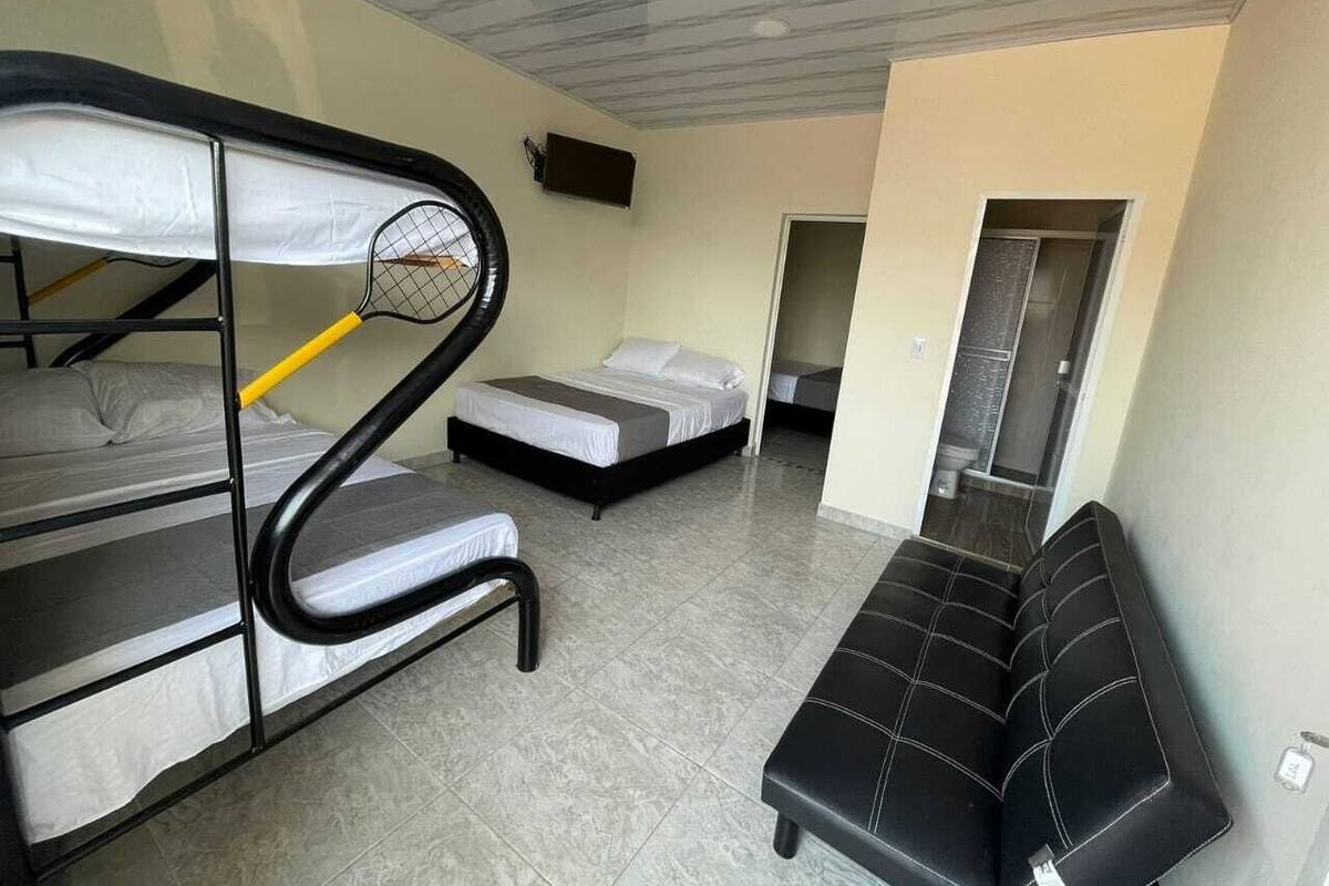 A dorm-style room with bunk beds, a bench, and a small seating area.