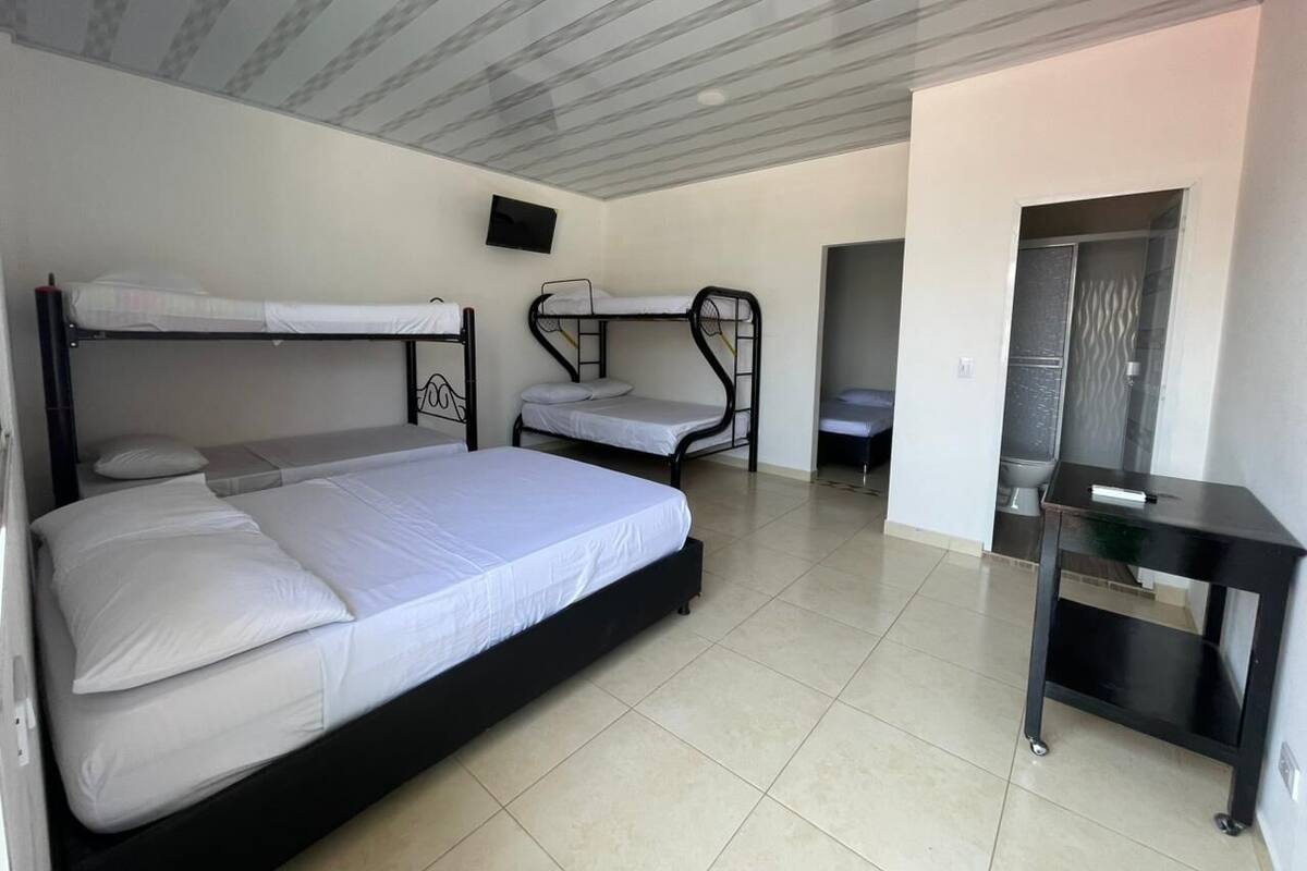 A room with bunk beds, a flat-screen TV, and a small table.