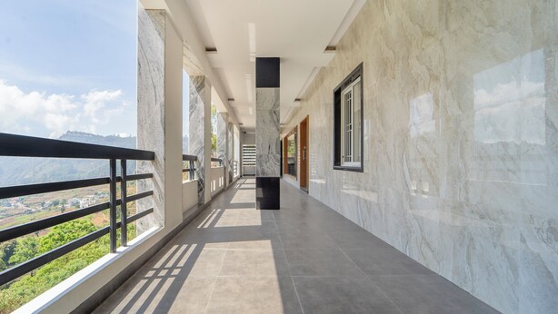 A corridor with marble walls and a balcony with a metal railing. - Treebo The Regalia Rooms With Mountain View (Kodaikanal)
