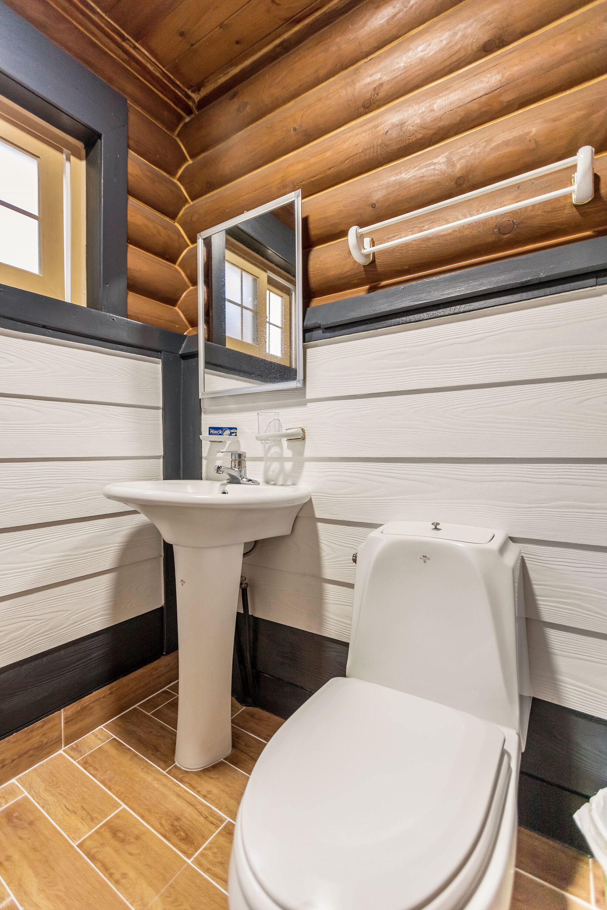 Un baño con techo de madera, un lavamanos blanco, un inodoro y un espejo.