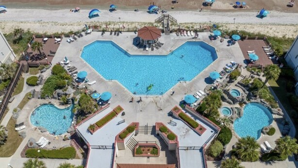 Ein Resort mit mehreren Schwimmbecken, Strandabschnitt und Liegestühlen.