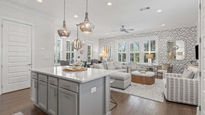 Una cocina amplia con una isla central, iluminación colgante y un ventilador de techo.