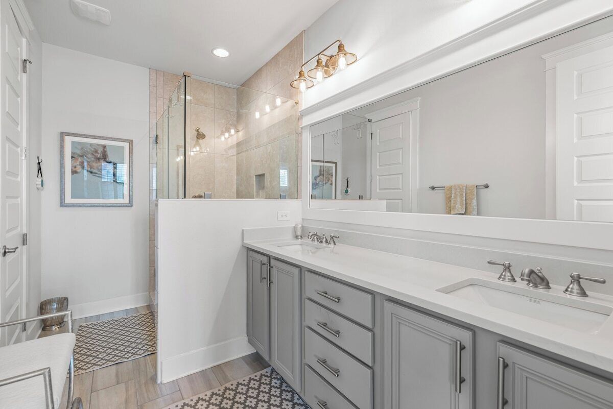 A modern bathroom with a large mirror, a walk-in shower, and a vanity with a sink.