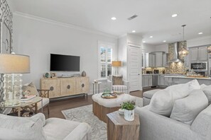 Un salon moderne avec un téléviseur à écran plat, un meuble en bois, un canapé et une table basse.