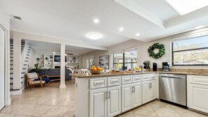 A spacious kitchen with white cabinetry, a central island, and a large window. - Luxury Home, Large Heated Pool, 5-Min to the Beach! (Seminole)