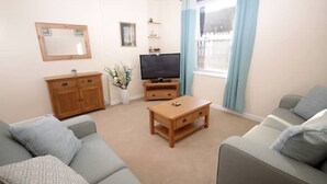 A living room with a sofa, a coffee table, a TV stand, and a cabinet.