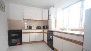 A kitchen with white cabinets, a black oven, a coffee maker, and a dishwasher.