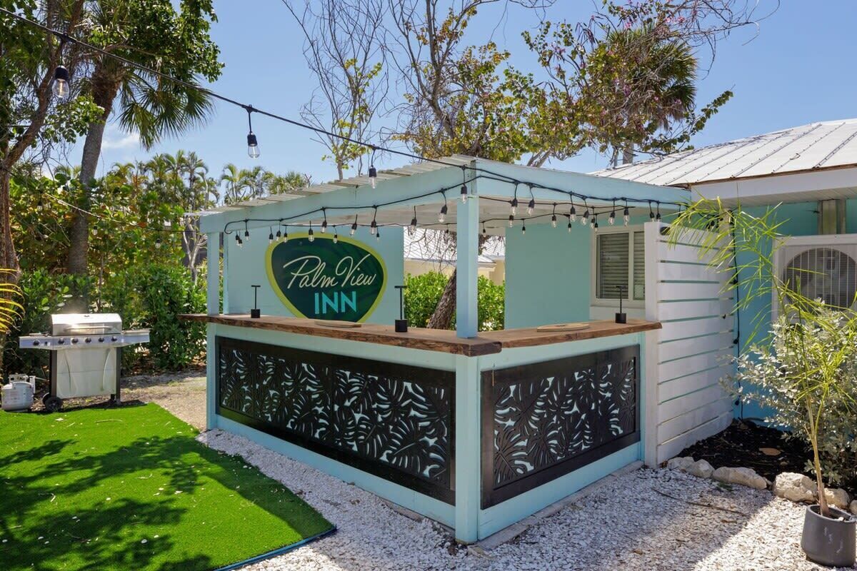 A Palm View Inn sign, a covered outdoor seating area, and a small building with a metal roof.