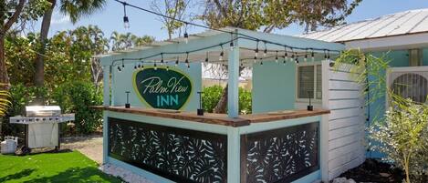 A Palm View Inn sign, a covered outdoor seating area, and a small building with a metal roof.