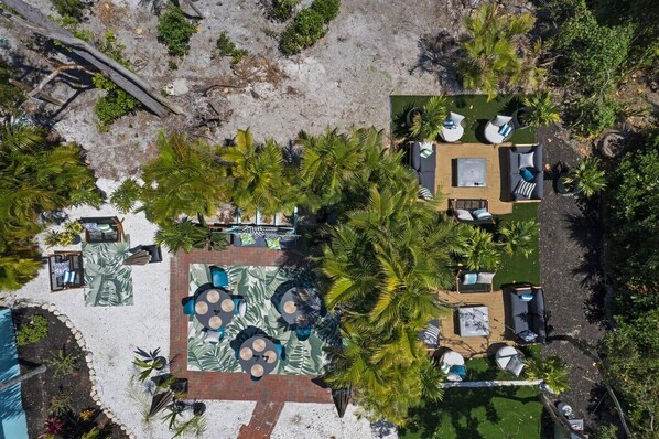 Vue aérienne d’un complexe hôtelier doté d’espaces de détente en plein air, d’une piscine et de palmiers.