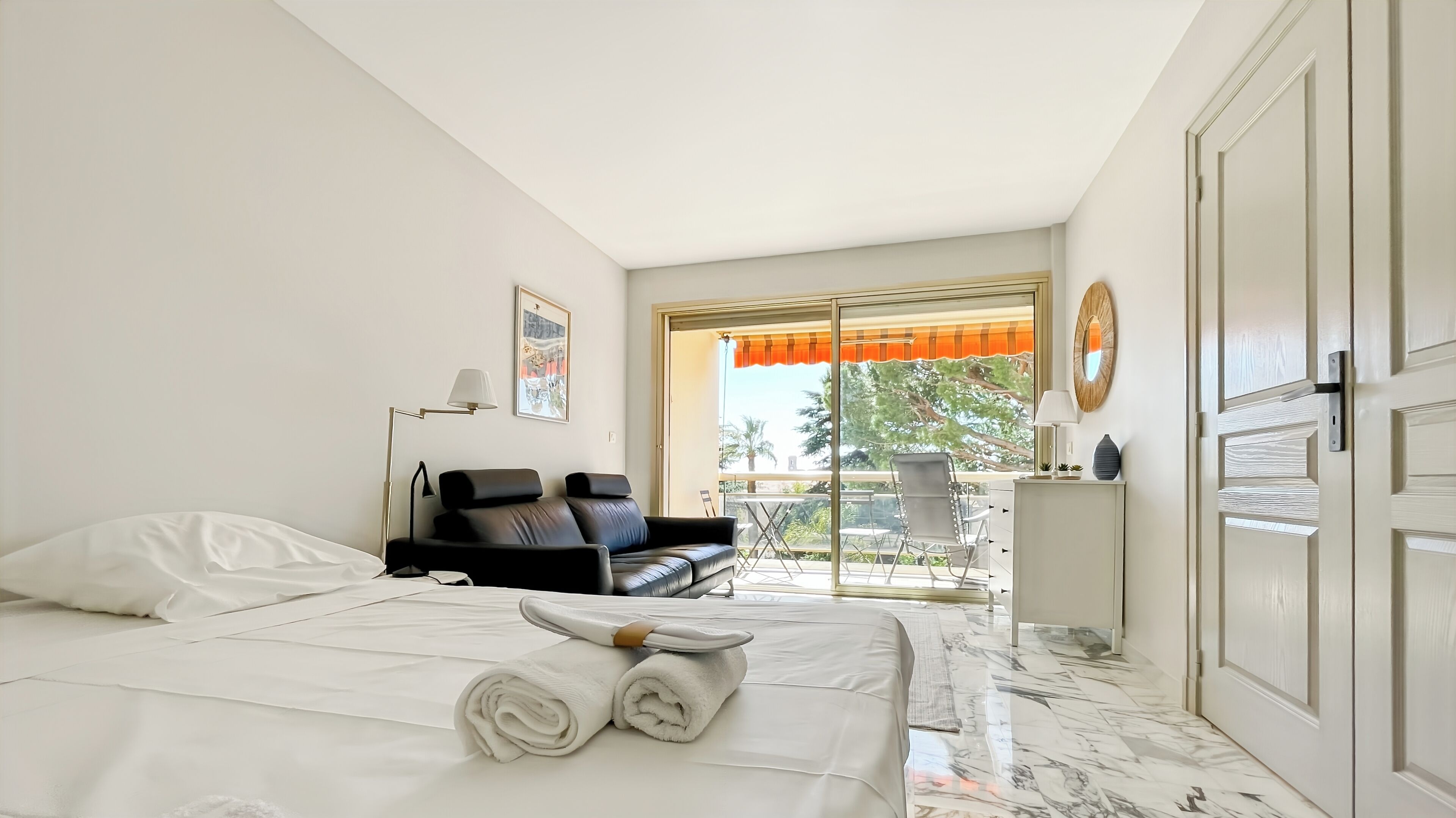 A hotel room with a bed, a sofa, a desk, and a balcony with a view.