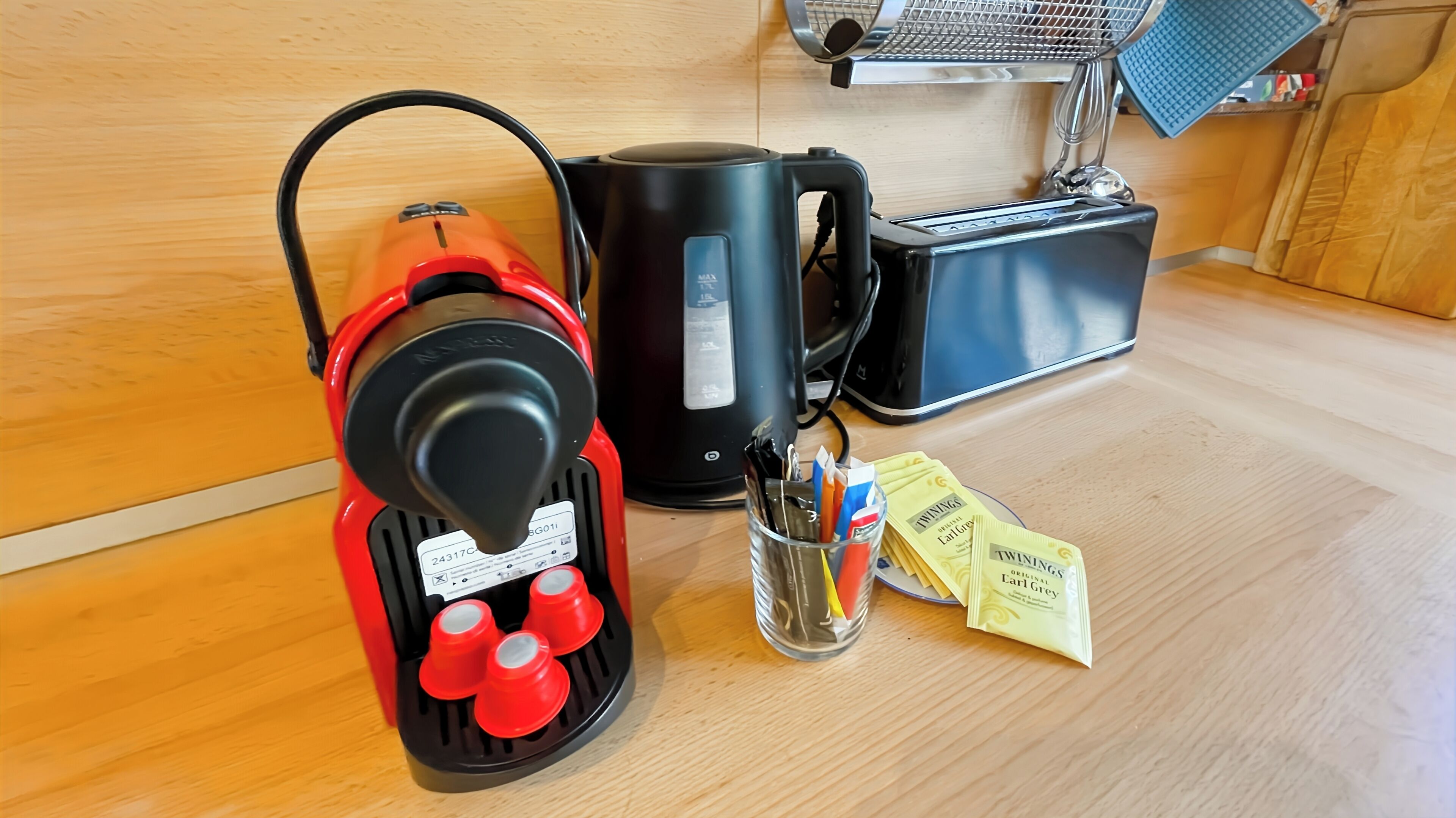 Ett kök med en kaffebryggare, en vattenkokare och te från Twinings i förpackningar på bänkskivan.