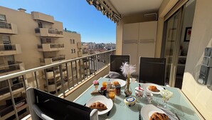 A balcony with a table set for breakfast, including croissants, orange juice, and a vase with flowers. - 2 Room modern, terrace and Parking (Cannes)