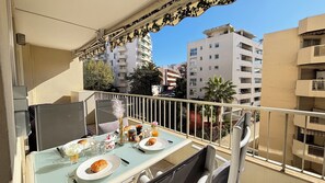 Varanda com mesa posta para o café da manhã, incluindo croissants, café e suco.