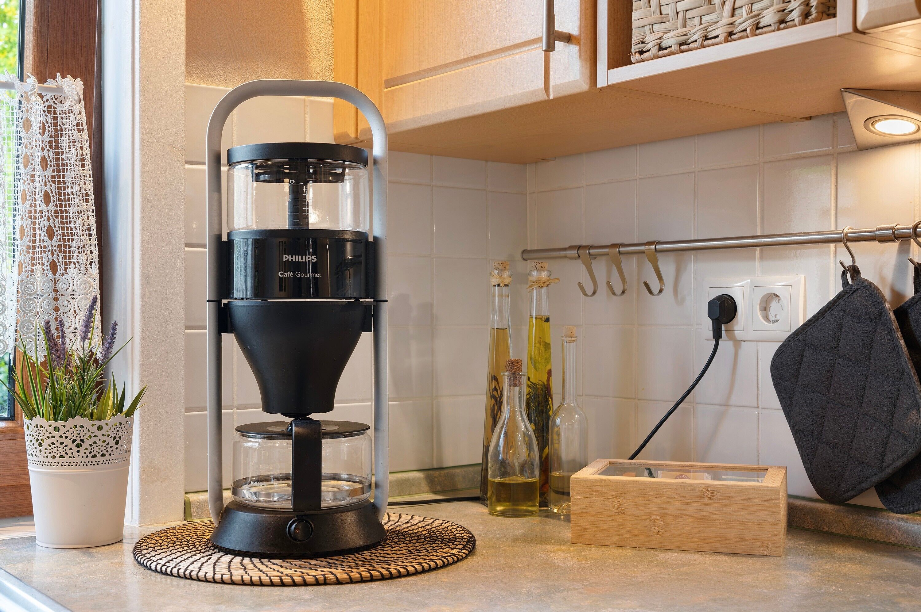 A coffee maker, a potted plant, and kitchen utensils on a countertop.