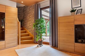 A modern interior with a wooden staircase, a large potted plant, and a stone wall. - Holiday Home 'Ferienhaus Thomas' with Shared Terrace, Shared Garden and Wi-Fi (Colnrade)