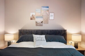 A neatly made bed with a pillow, a headboard, bedside lamps, and wall art. - Holiday Home 'Ferienhaus Thomas' with Shared Terrace, Shared Garden and Wi-Fi (Colnrade)